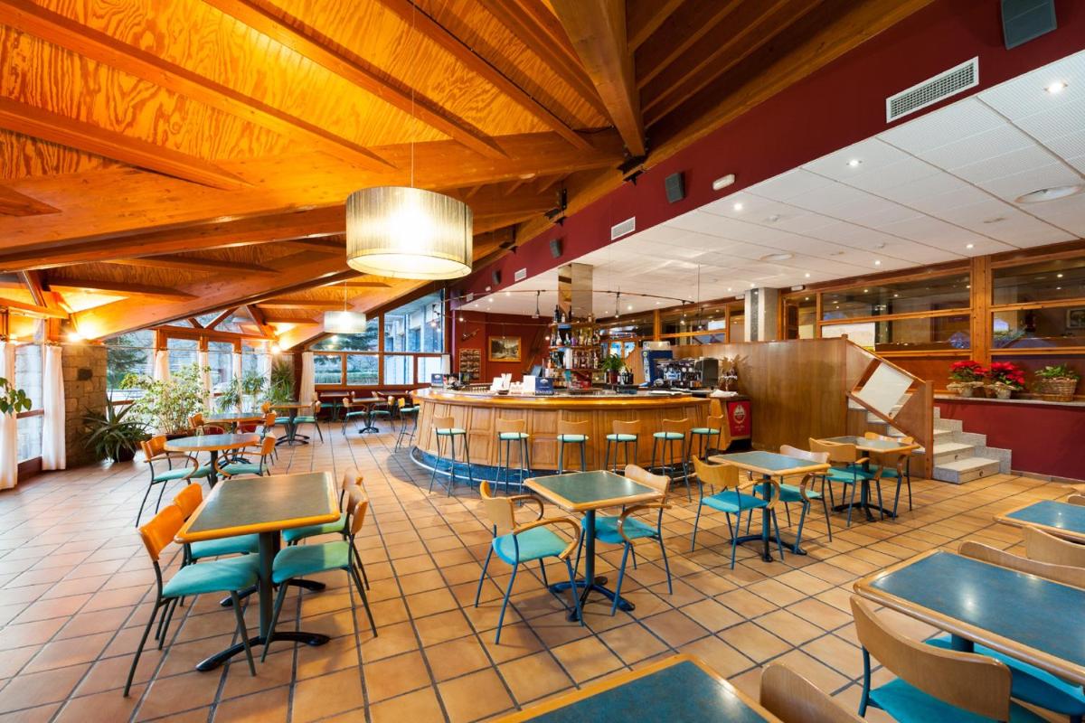 Un restaurante con mesas y sillas y un bar. en SOMMOS Hotel Benasque Spa, en Benasque