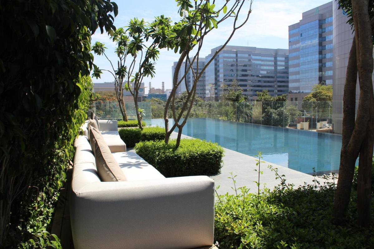 a row of white couches sitting next to a pool at The Den, Bengaluru in Bengaluru