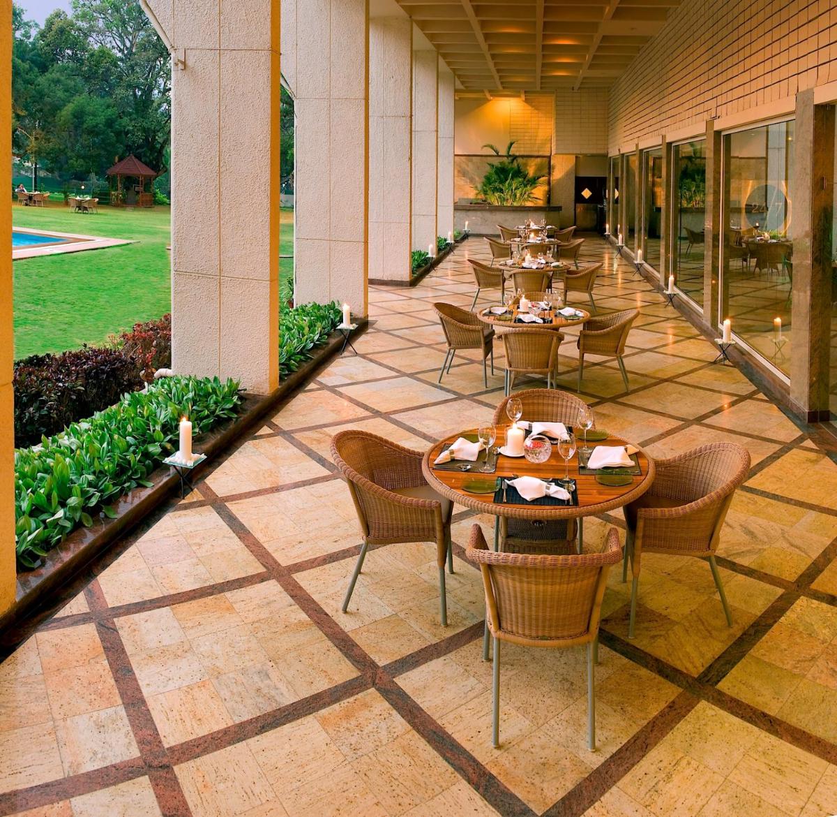 a restaurant with tables and chairs on a patio at The Lalit Ashok in Bengaluru a restaurant with tables and chairs on a patio at The Lalit Ashok in Bengaluru