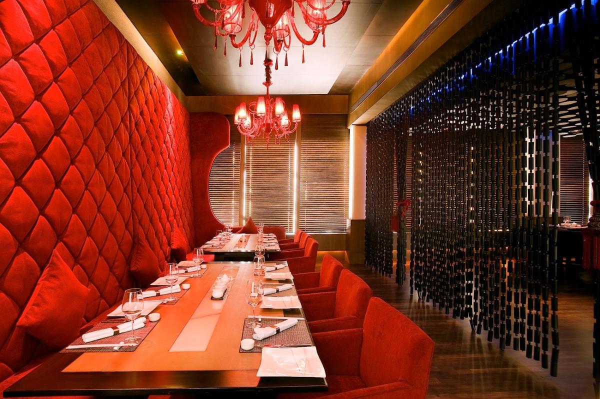 a dining room with a long table and red walls at The Lalit Ashok in Bengaluru a dining room with a long table and red walls at The Lalit Ashok in Bengaluru
