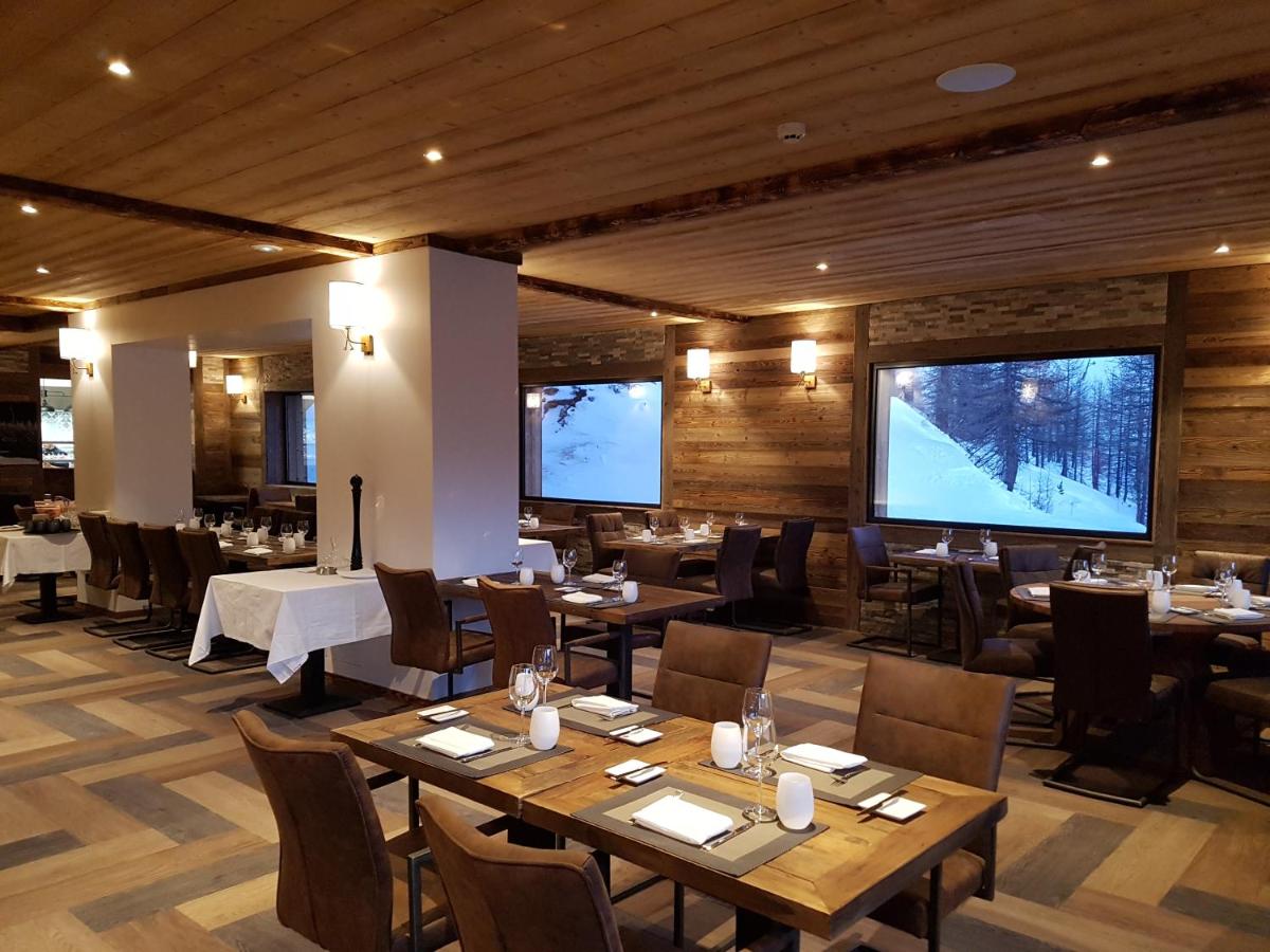un restaurant avec des tables et des chaises et un grand écran dans l'établissement Chalet Marano Restaurant & Spa, à Isola 2000
