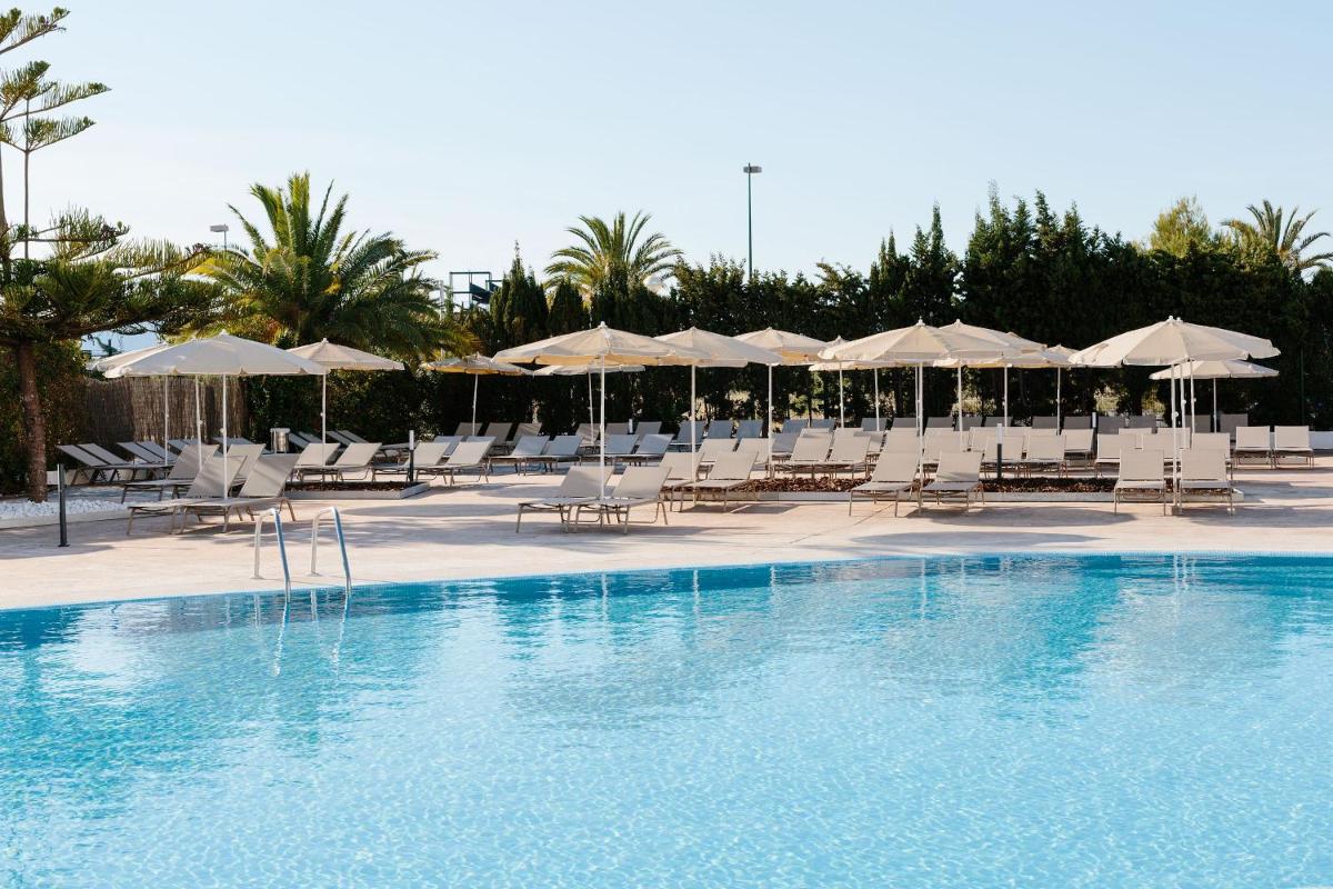 una piscina con sillas blancas y sombrillas en Bordoy Alcudia Bay - Adults Only, en Puerto de Alcudia