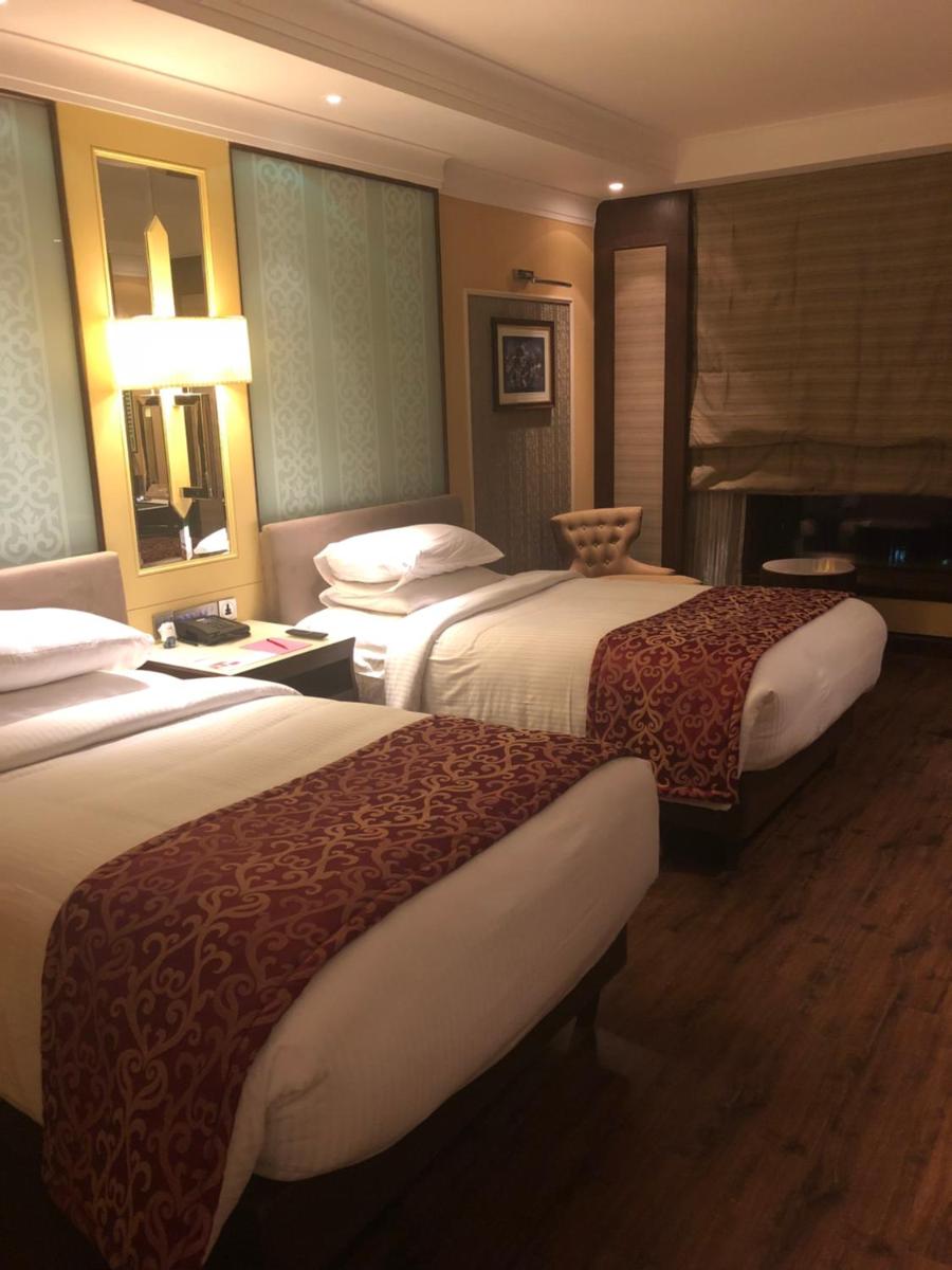 a hotel room with two beds and a mirror at Ramada Plaza Chennai in Chennai