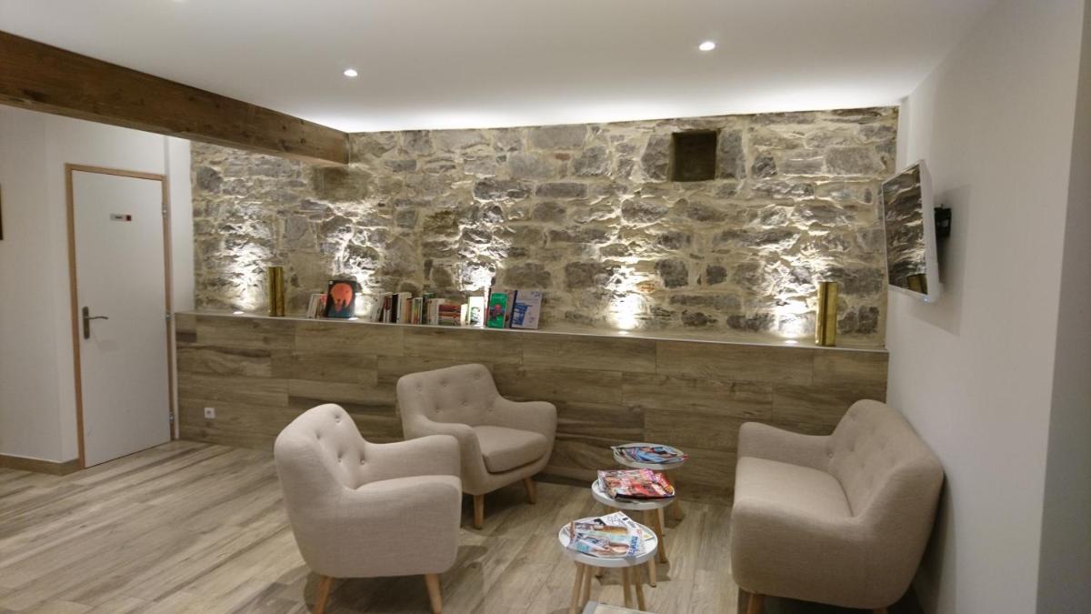 un salon avec des chaises et une table et un mur en pierre dans l'établissement Le Moulin d'Oscar & Spa - Mulhouse Nord, à Baldersheim