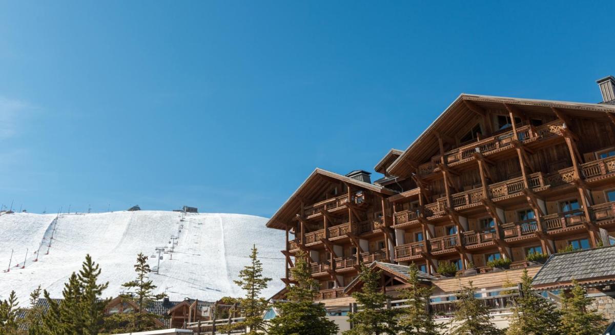 un lodge de ski en face d'une montagne enneigée dans l'établissement Hôtel Au Chamois d'Or by Les Etincelles, à L'Alpe-d'Huez
