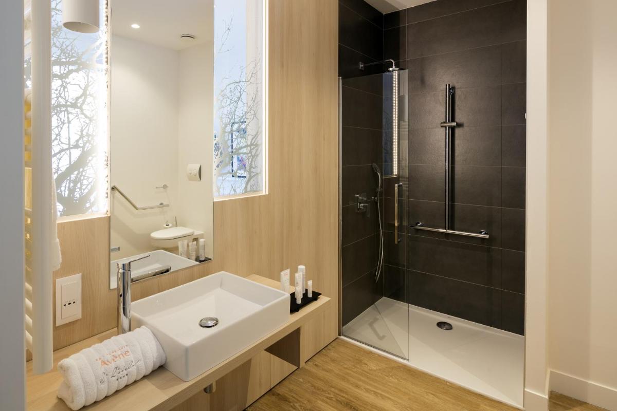une salle de bain avec un lavabo blanc et une douche dans l'établissement Eau Thermale Avène l'hôtel, à Avène