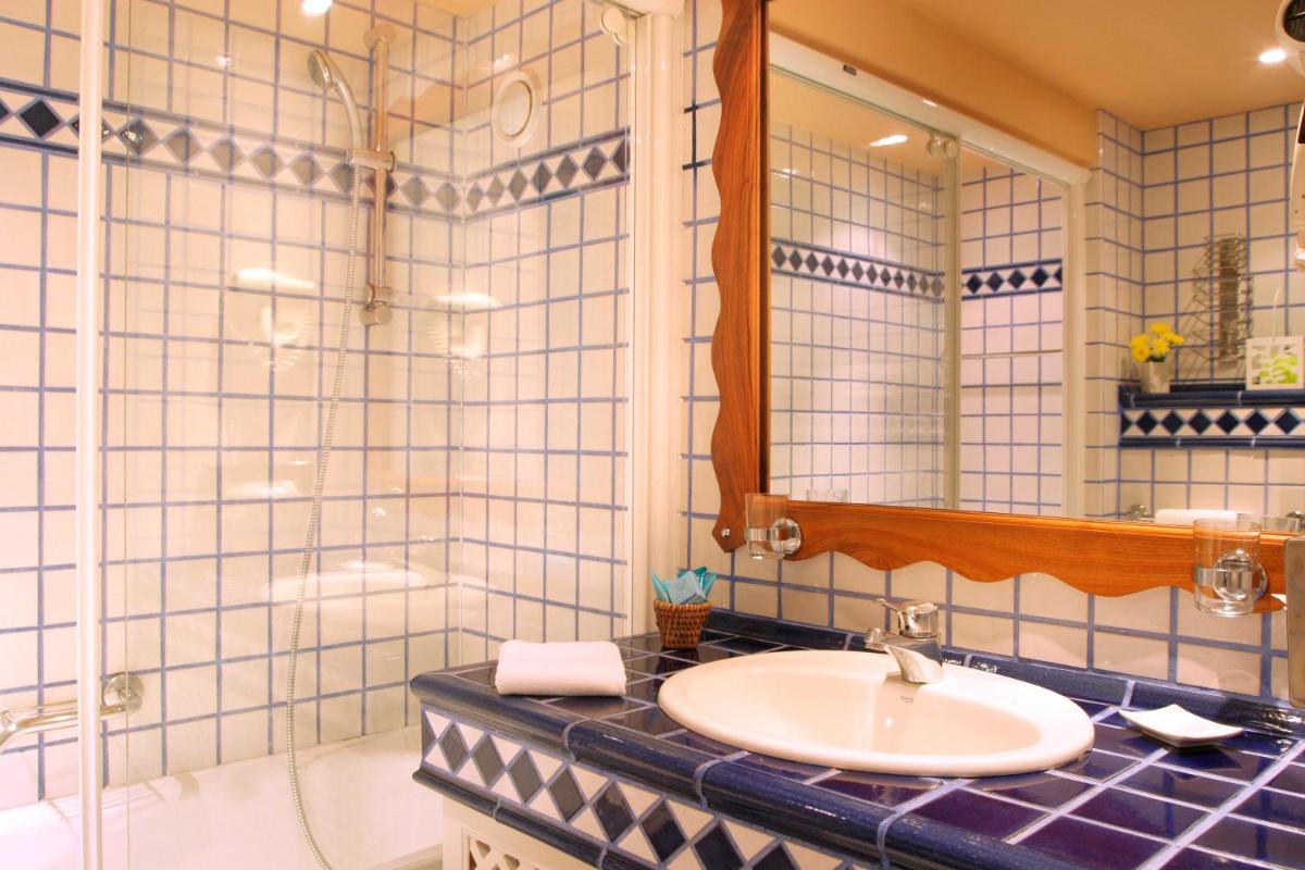 une salle de bains avec lavabo, baignoire et miroir dans l'établissement Le Domaine de Falgos Golf & Spa, à Saint-Laurent-de-Cerdans