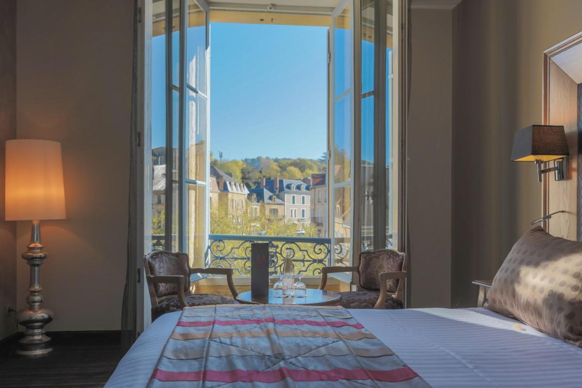 une chambre avec un lit et une grande fenêtre dans l'établissement Plaza Madeleine & Spa, à Sarlat-la-Canéda