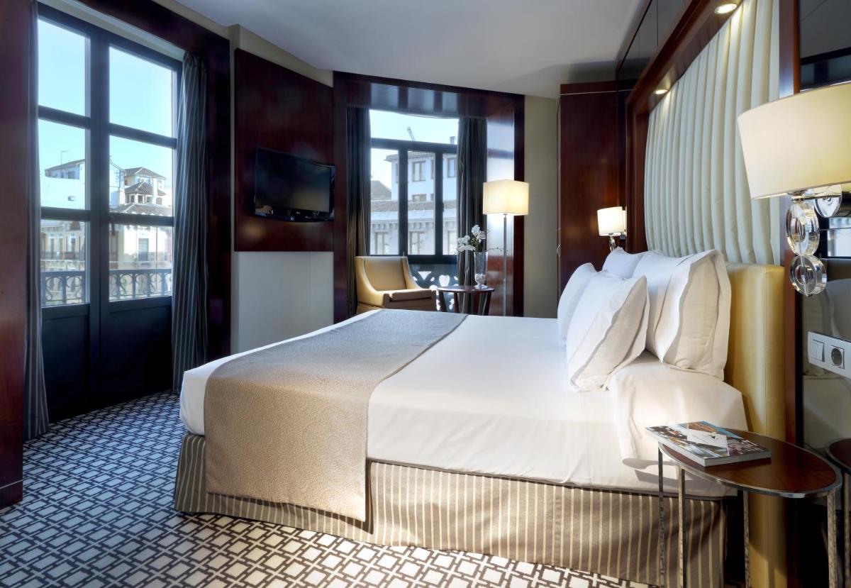 Una habitación de hotel con una cama y una ventana grande. en Eurostars Gran Via, en Granada