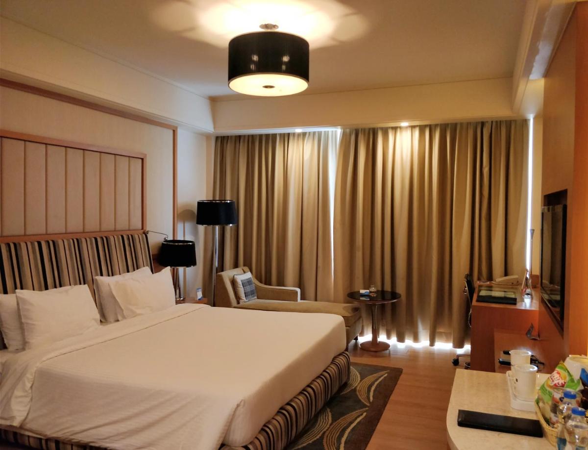 a bedroom with a large white bed and a chair at Radisson Blu Hotel, Nagpur in Nagpur