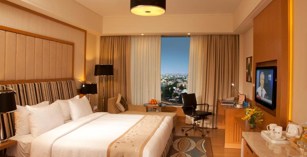 a hotel room with a large bed and a desk at Radisson Blu Hotel, Nagpur in Nagpur