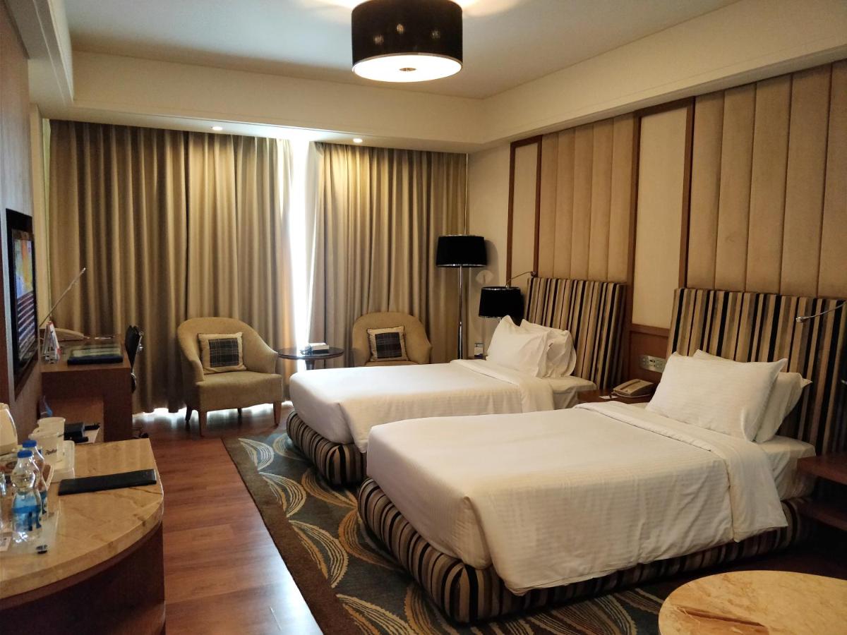 a hotel room with two beds and a table at Radisson Blu Hotel, Nagpur in Nagpur