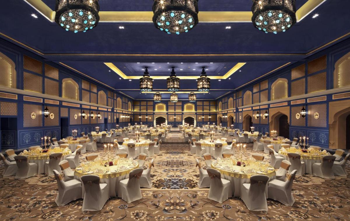 a ballroom with tables and chairs and chandeliers at Fairmont Jaipur in Jaipur