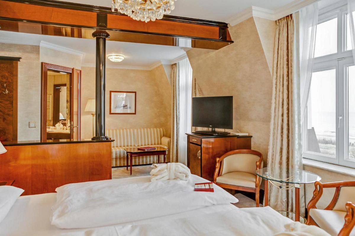 ein Hotelzimmer mit einem Bett und einem Spiegel in der Unterkunft SEETELHOTEL Ahlbecker Hof das elegante Traditionshotel & ruhiger Rückzugsort an der Ostsee in Ahlbeck + 37 Fotos