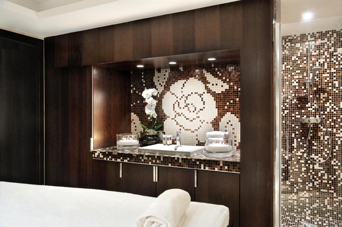 La salle de bains est pourvue de 2 lavabos et d'un mur en mosaïque. dans l'établissement Hotel Le Savoy, à Méribel