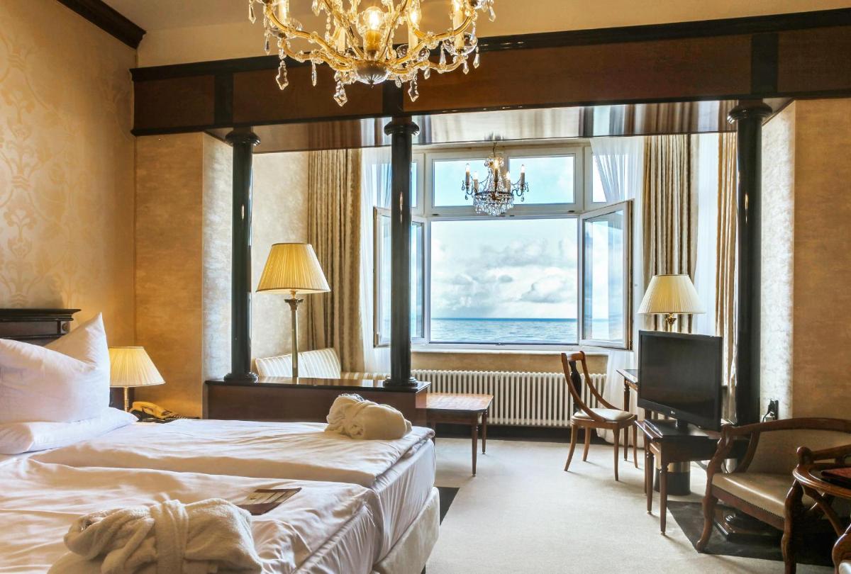 ein Schlafzimmer mit einem Bett, einem Schreibtisch und einem Fenster in der Unterkunft SEETELHOTEL Ahlbecker Hof das elegante Traditionshotel & ruhiger Rückzugsort an der Ostsee in Ahlbeck
