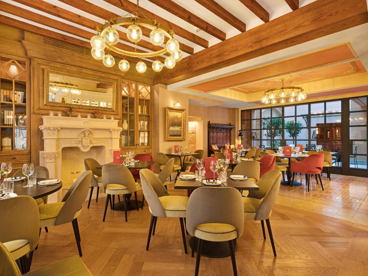 Un restaurante con mesas y sillas y chimenea. en Hotel Gloria de Sant Jaume, en Palma de Mallorca