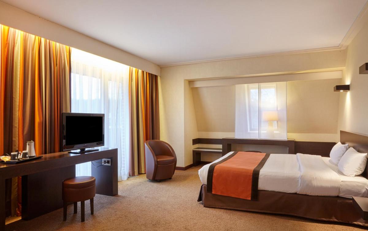 une chambre d'hôtel avec un lit, un bureau et une télévision dans l'établissement Hôtel Spa Du Béryl, à Bagnoles-de-l'Orne
