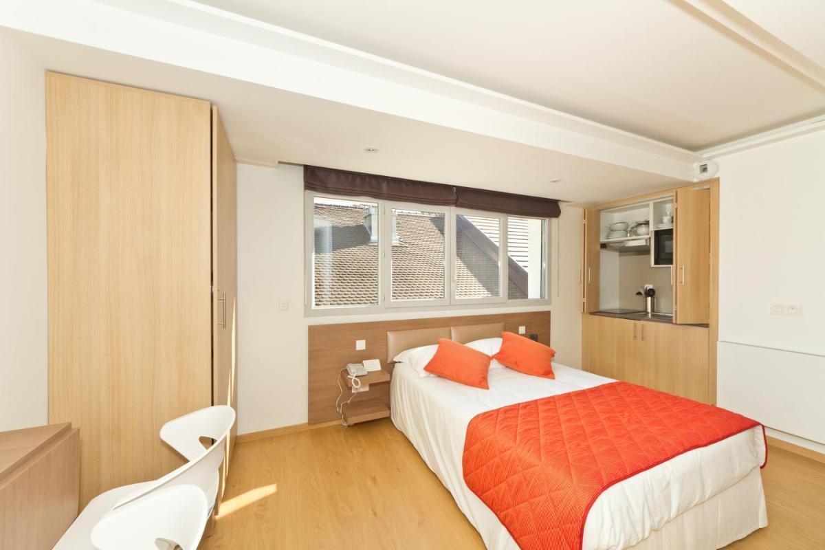 une chambre avec un grand lit avec des oreillers orange dans l'établissement Villa Thermae Thonon-Les-Bains, à Thonon-les-Bains
