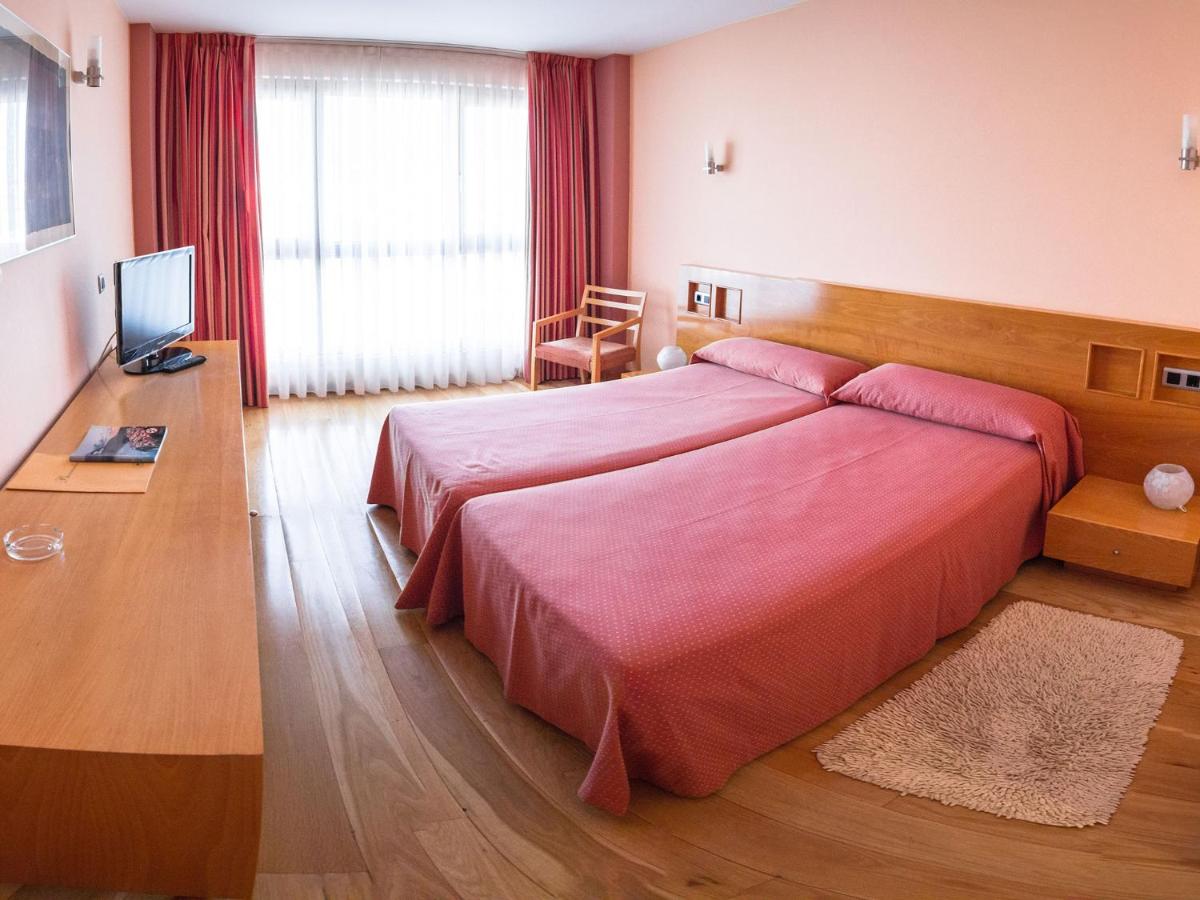 1 dormitorio con 1 cama rosa grande y escritorio en Hotel La Estación de Luanco, en Luanco