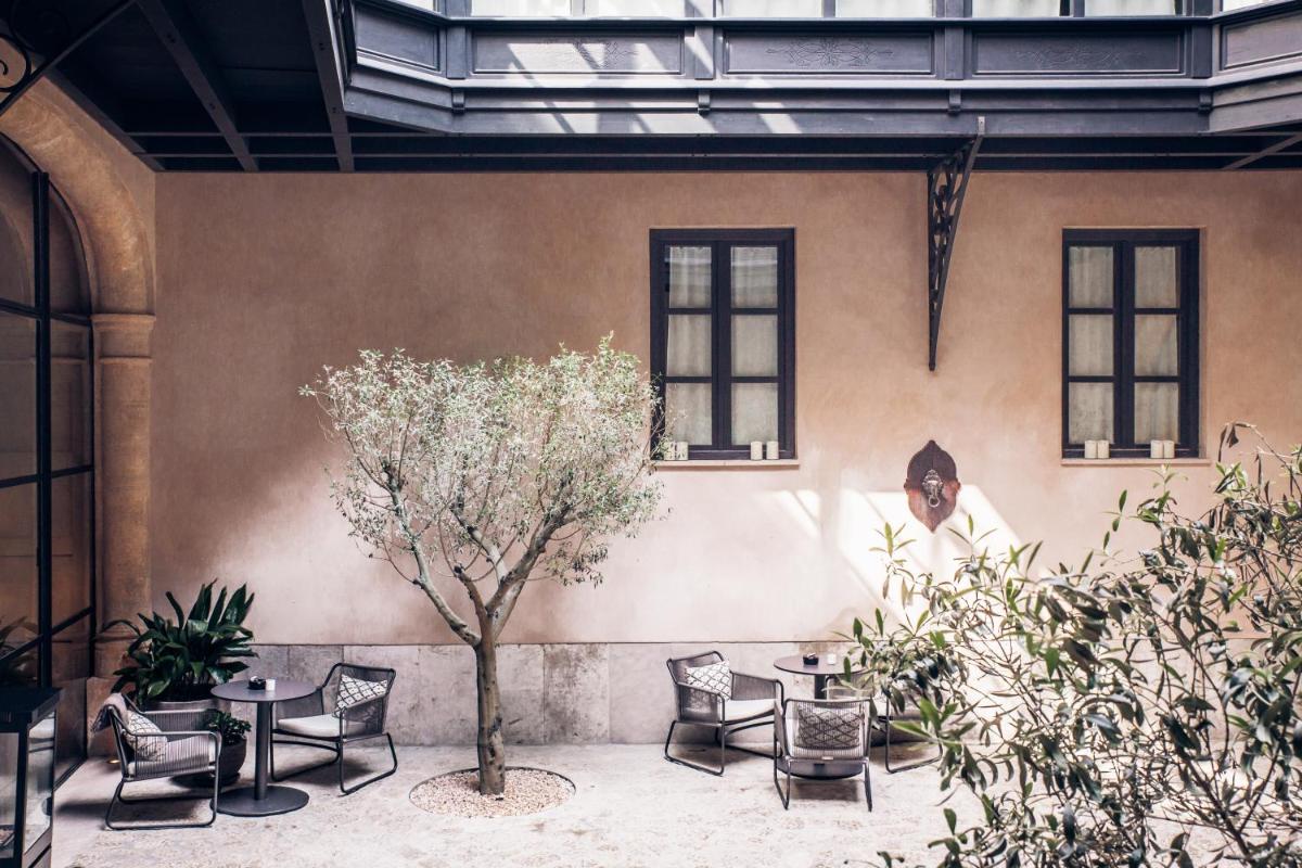Un patio con mesas y sillas y un árbol. en Sant Francesc Hotel Singular, en Palma de Mallorca
