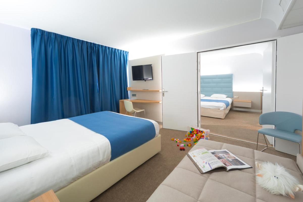 une chambre d'hôtel avec un lit et une chaise dans l'établissement Hotel Plaza - site du Futuroscope, à Chasseneuil-du-Poitou
