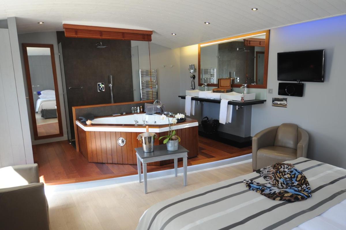 - une chambre avec une salle de bains pourvue d'une baignoire et d'un lit dans l'établissement Elégance Suites Hôtel, au Bois-Plage-en-Ré