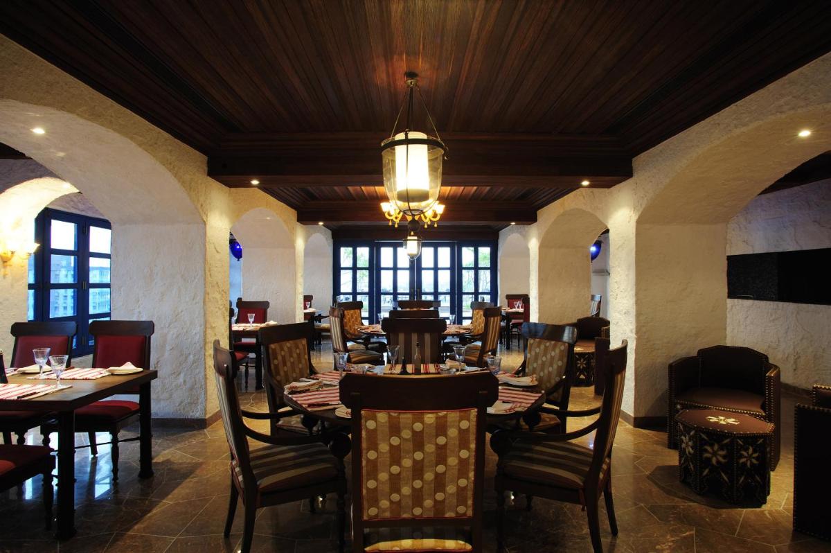 a dining room with tables and chairs and a chandelier at Taj Club House in Chennai