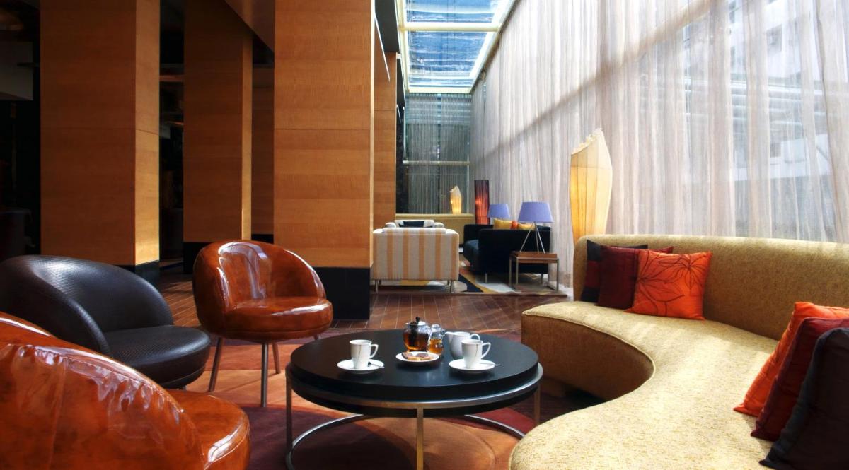 a lobby with leather chairs and a table with coffeeisers at Taj Club House in Chennai