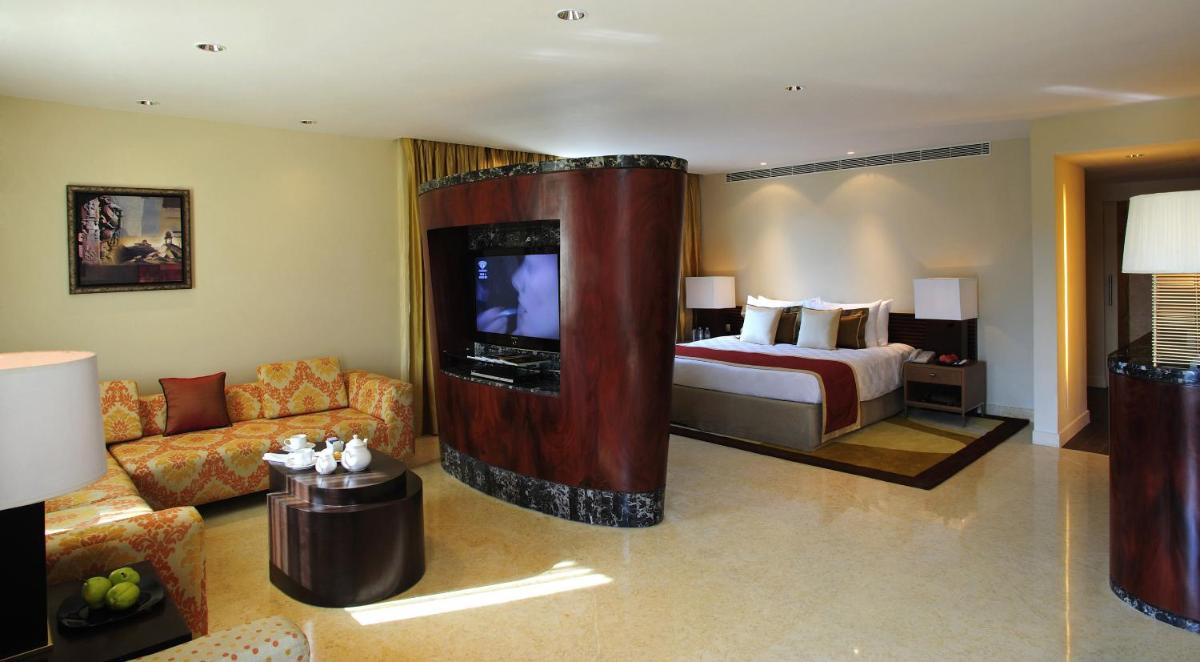 a living room with a bed and a tv in a room at Taj Club House in Chennai a living room with a bed and a tv in a room at Taj Club House in Chennai