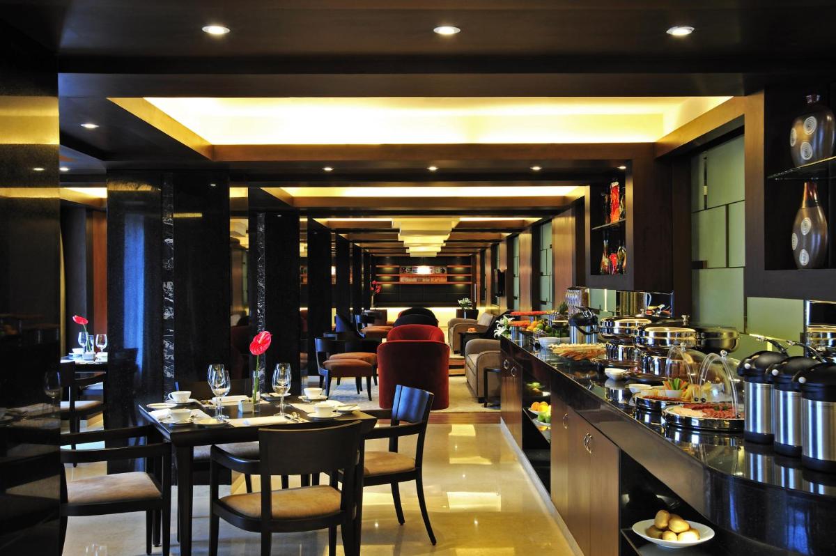 a restaurant with a bar with tables and chairs at Taj Club House in Chennai