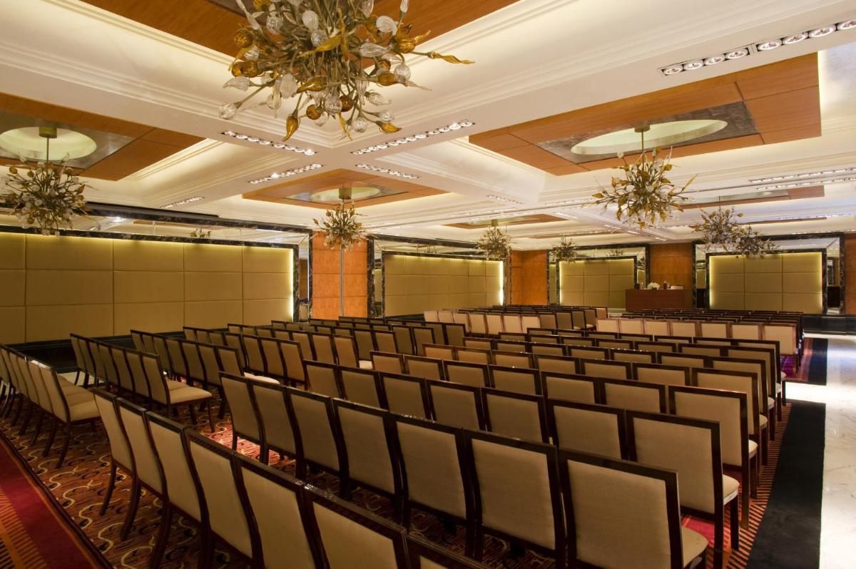 a room with rows of chairs and a chandelier at Taj Club House in Chennai