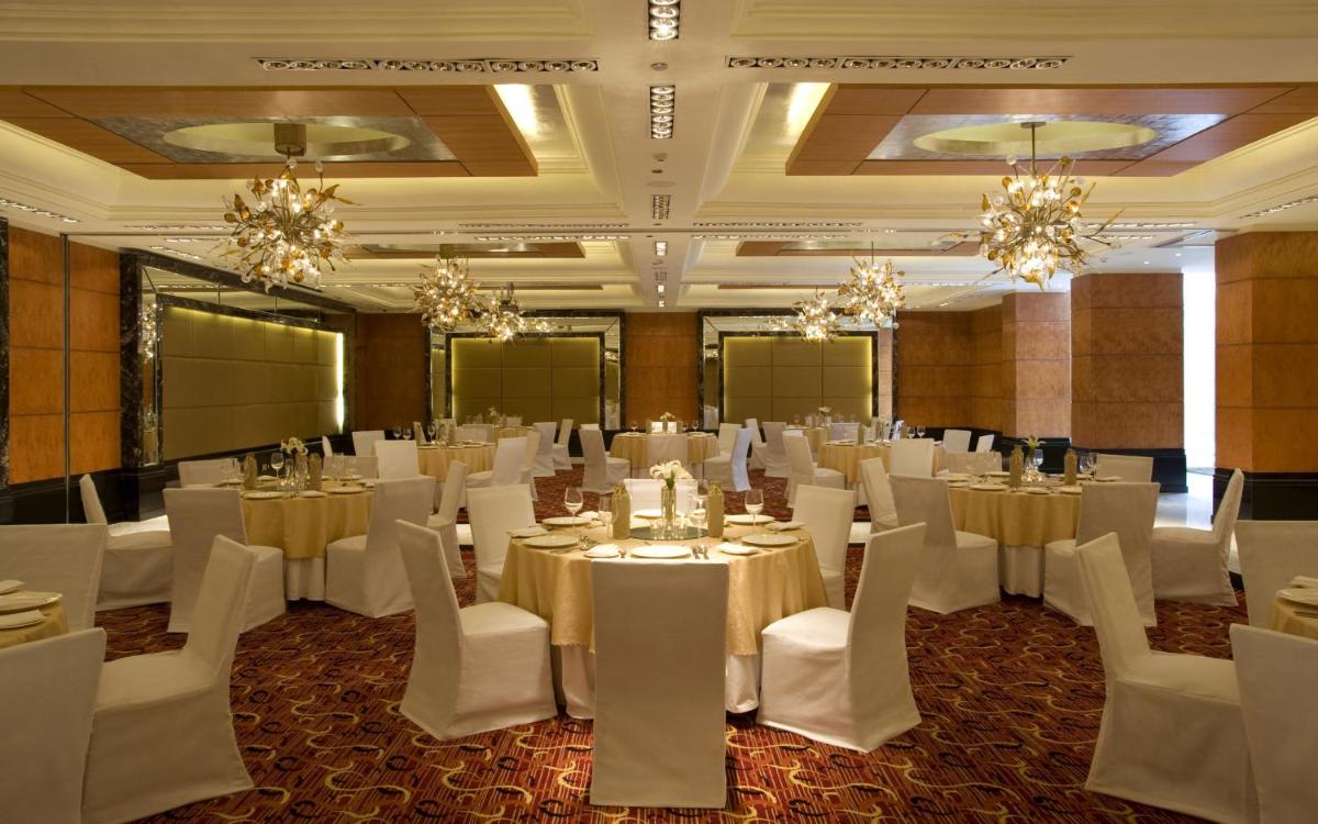 a banquet hall with white tables and chairs and chandeliers at Taj Club House in Chennai