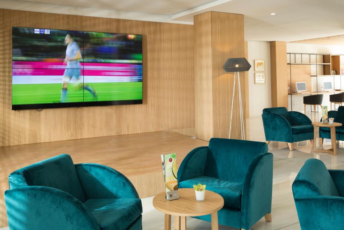 sala de estar con sillas azules y TV en la pared en JS Alcudi-Mar, en Playa de Muro