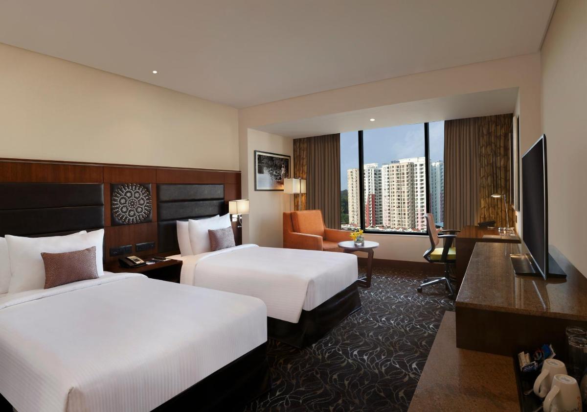 a hotel room with two beds and a television at Novotel Kochi Infopark in Cochin