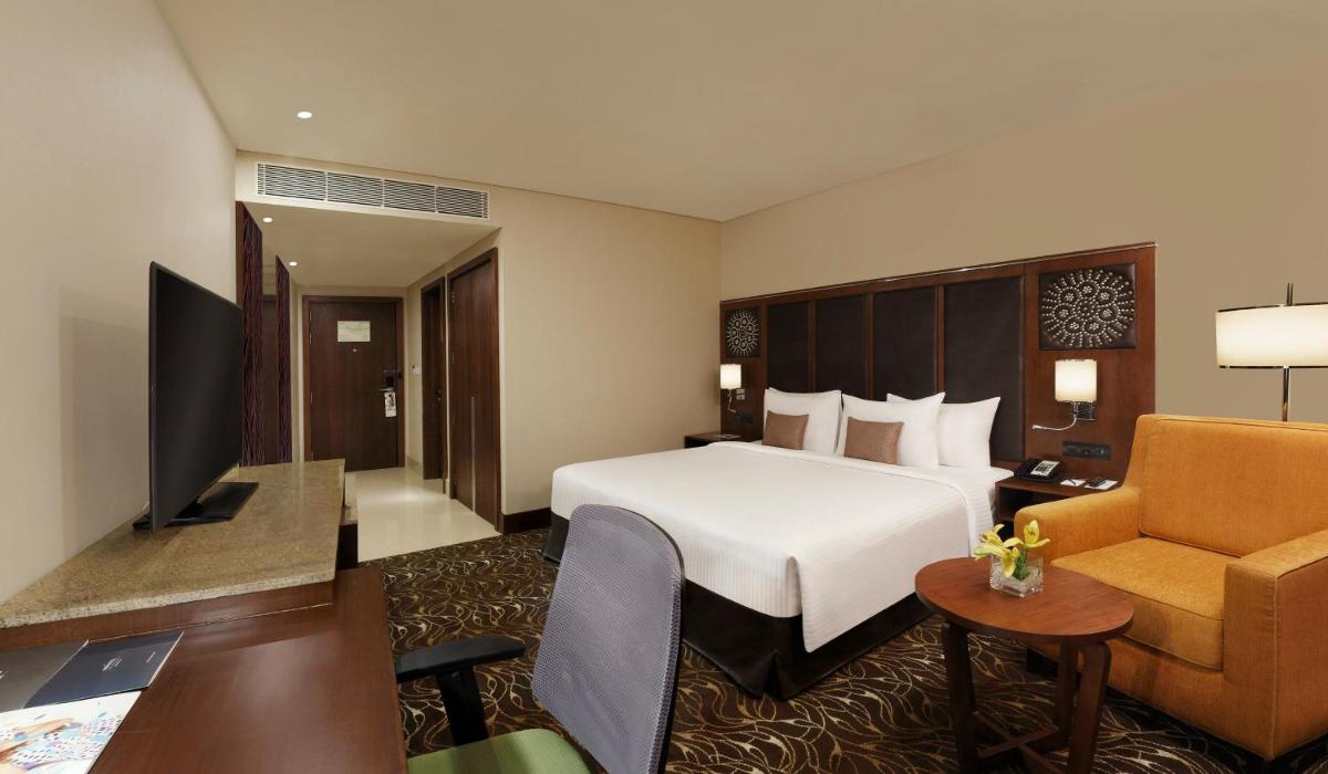 a hotel room with a bed and a couch and a chair at Novotel Kochi Infopark in Cochin