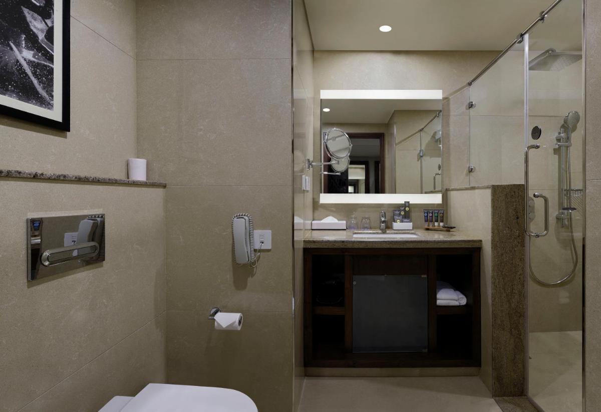 a bathroom with a shower and a toilet and a sink at Novotel Kochi Infopark in Cochin