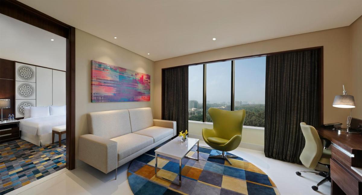 a living room with a couch and a chair and a desk at Novotel Kochi Infopark in Cochin