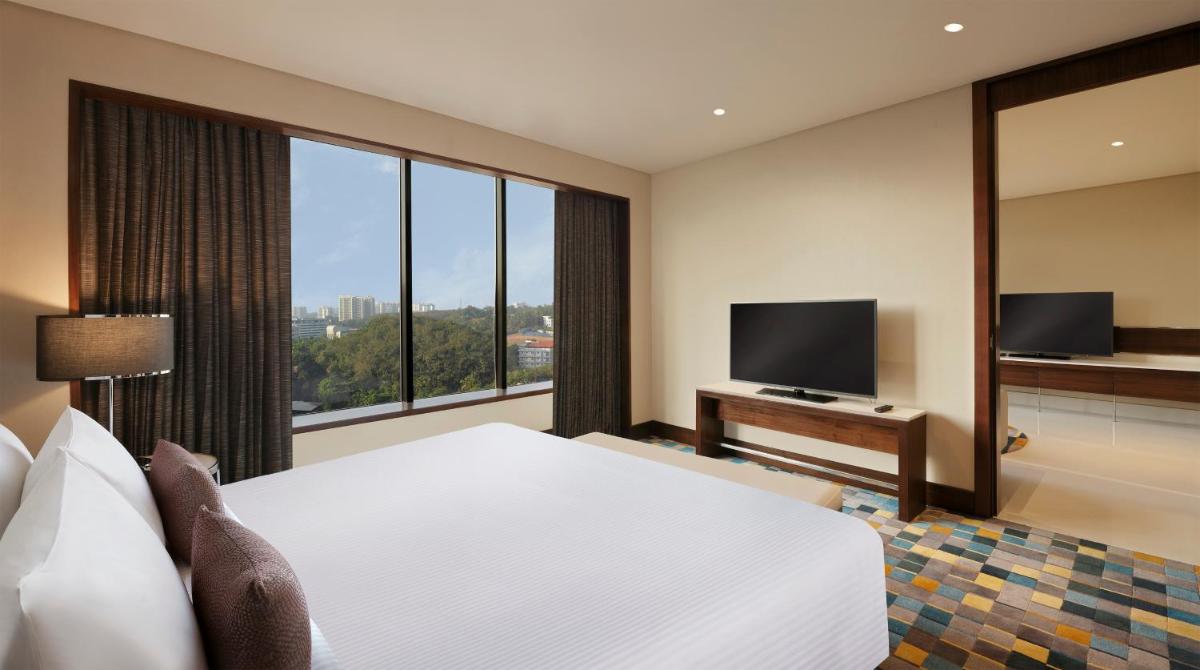 a hotel room with a large bed and a large window at Novotel Kochi Infopark in Cochin