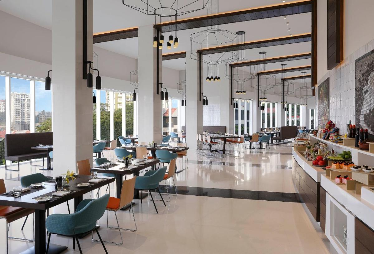 a rendering of a restaurant with tables and chairs at Novotel Kochi Infopark in Cochin