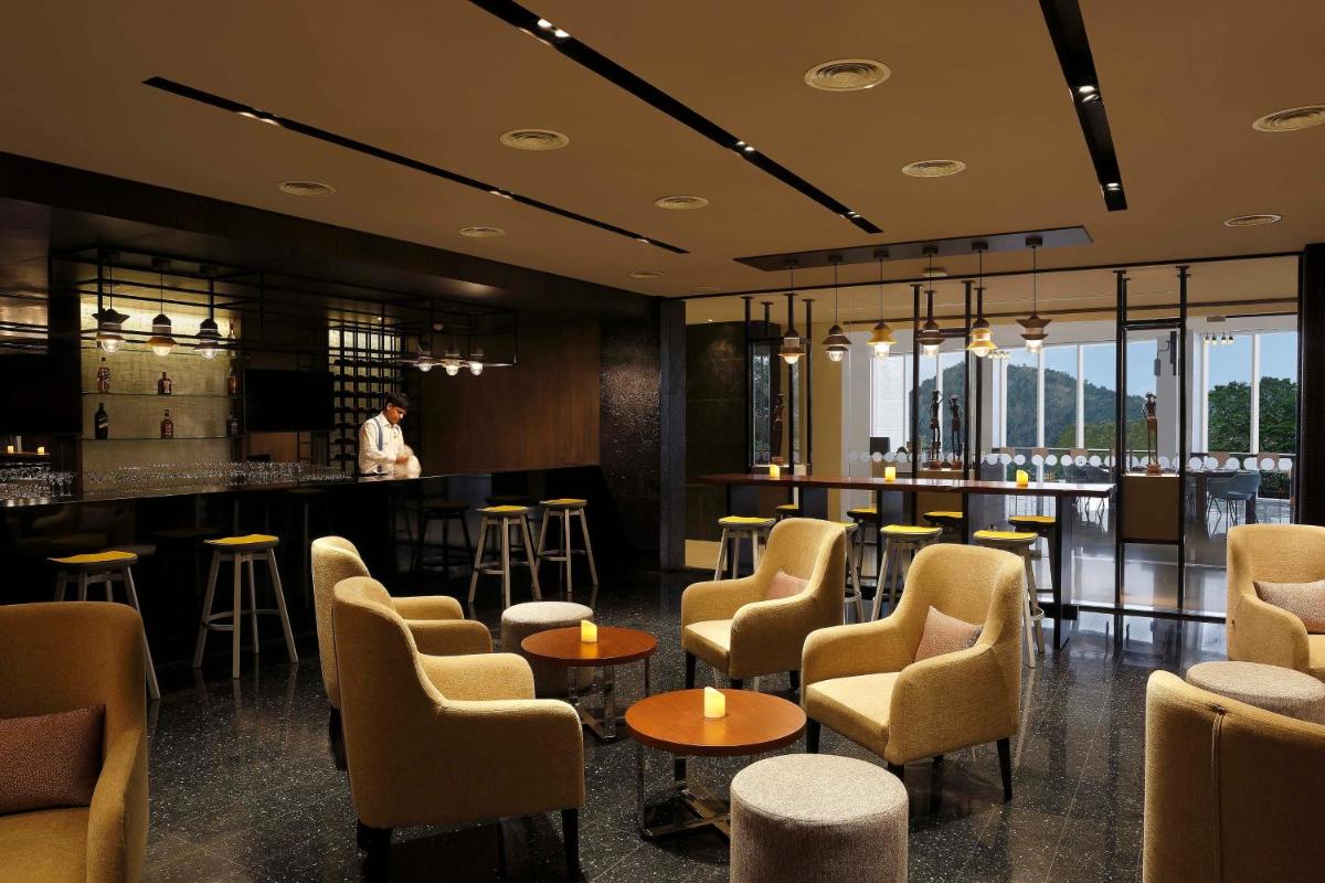 a restaurant with chairs and a bar with a person in the background at Novotel Kochi Infopark in Cochin