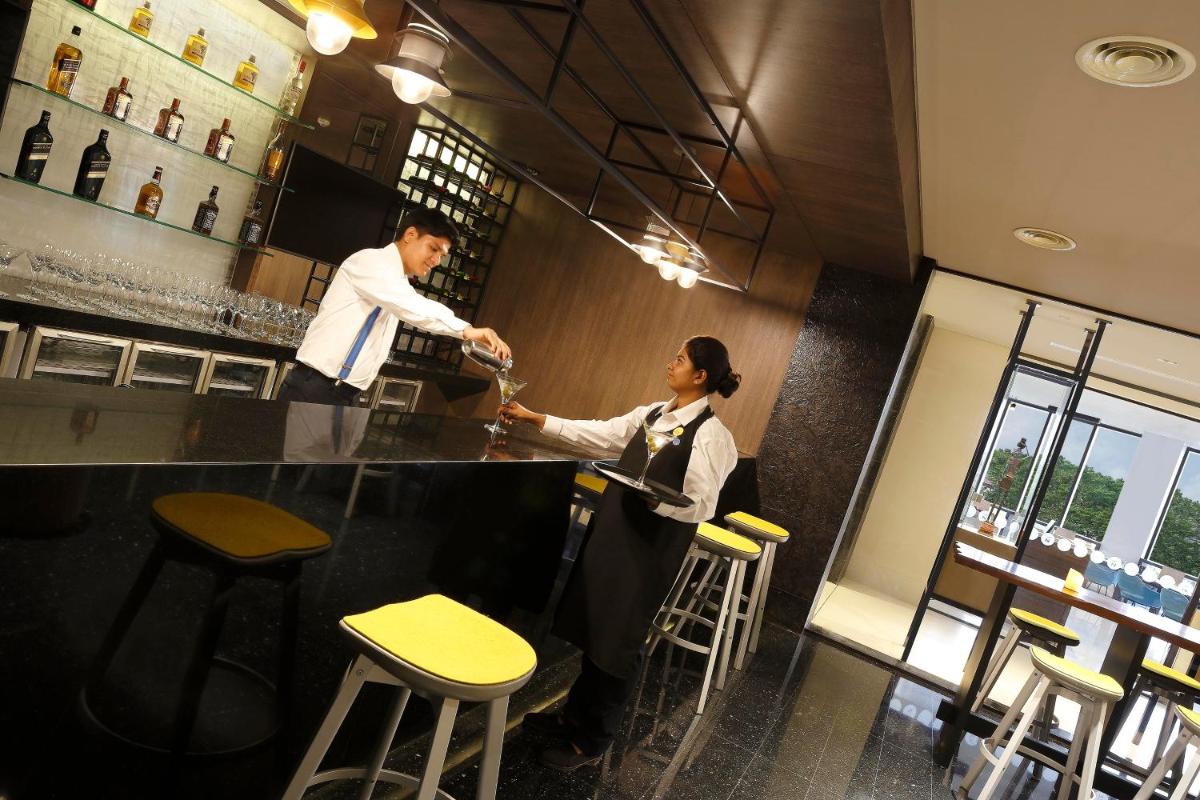 a man and a woman standing at a bar at Novotel Kochi Infopark in Cochin