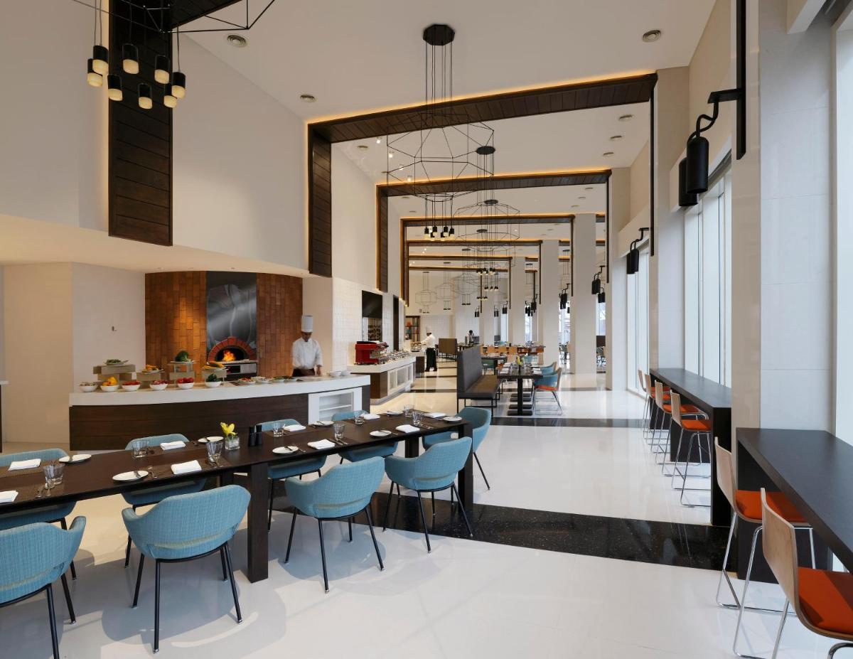 a restaurant with a long table and blue chairs at Novotel Kochi Infopark in Cochin