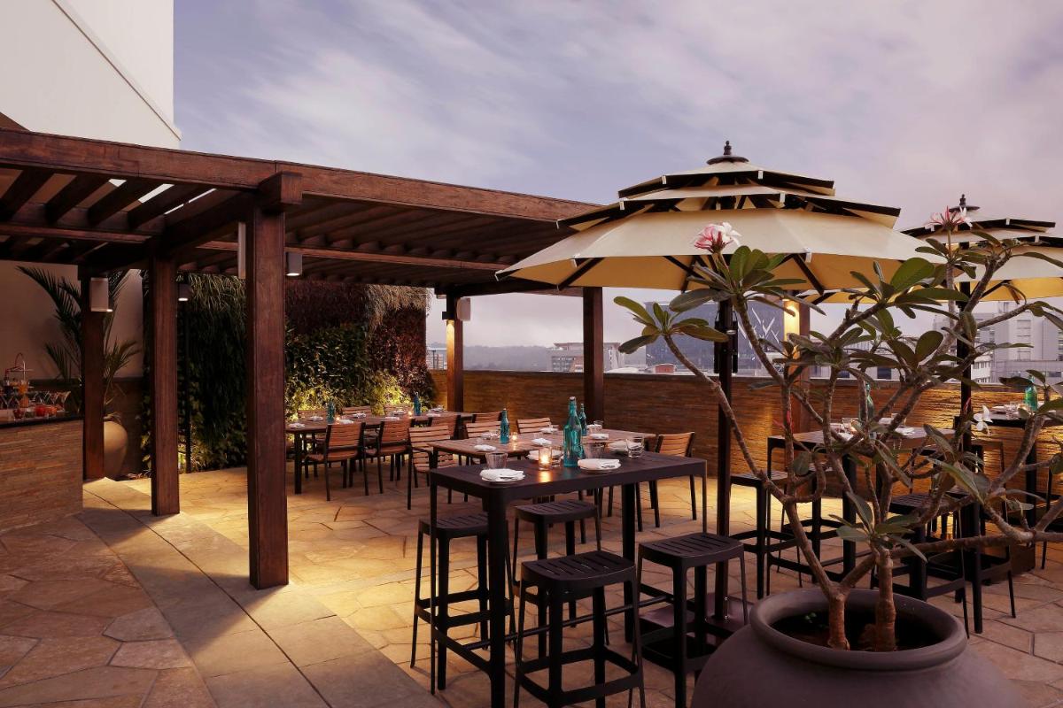 a restaurant with tables and chairs and an umbrella at Novotel Kochi Infopark in Cochin