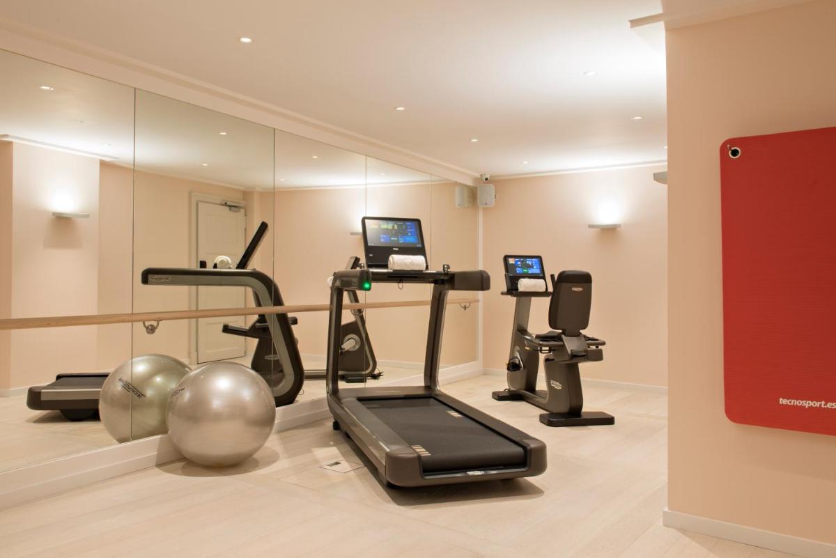 un gimnasio con cinta de correr y espejo en Hotel Cappuccino - Palma, en Palma de Mallorca