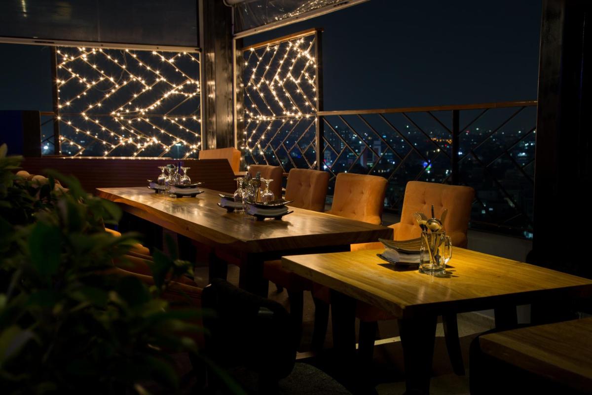 two wooden tables in a restaurant with lights on the wall at The Accord Metropolitan in Chennai