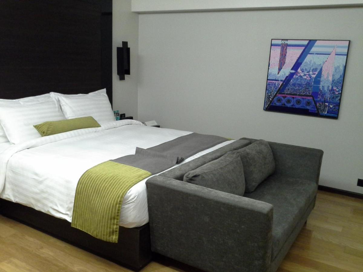 a bedroom with a bed and a couch in it at Svenska Design Hotel in Mumbai