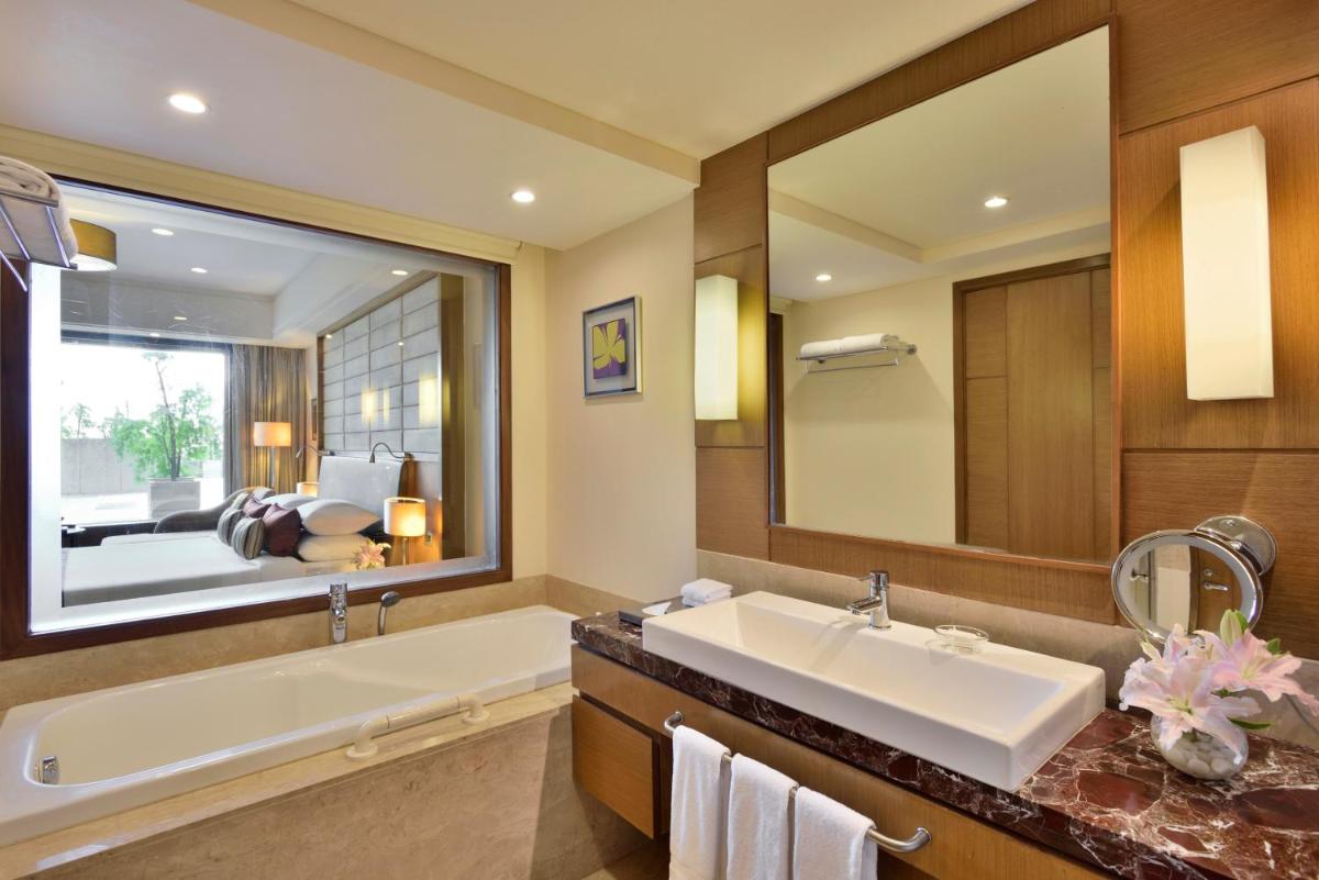 a bathroom with a large mirror and a tub and a sink at Radisson Blu Hotel, Indore in Indore