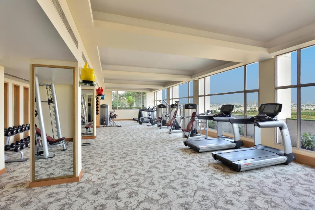 a gym with treadmills and ellipticals in a room with windows at Radisson Blu Hotel, Indore in Indore