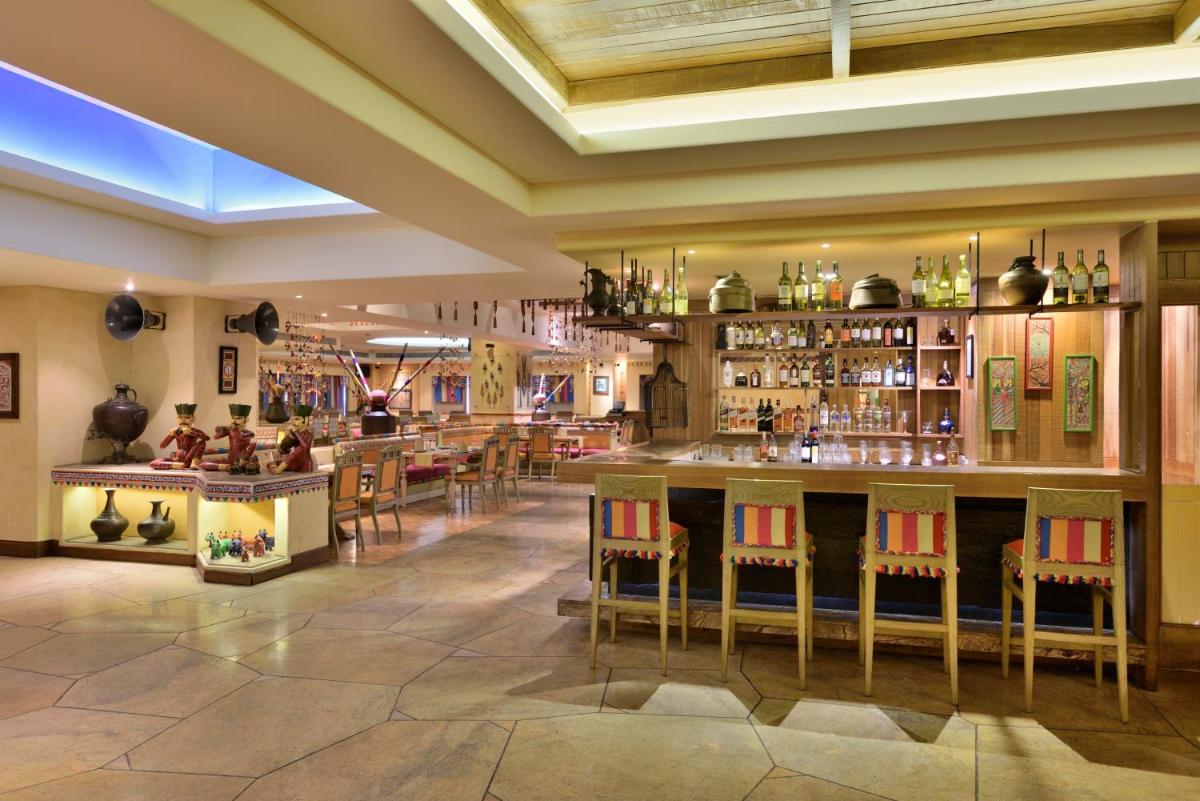 a restaurant with a bar with chairs and tables at Radisson Blu Hotel, Indore in Indore